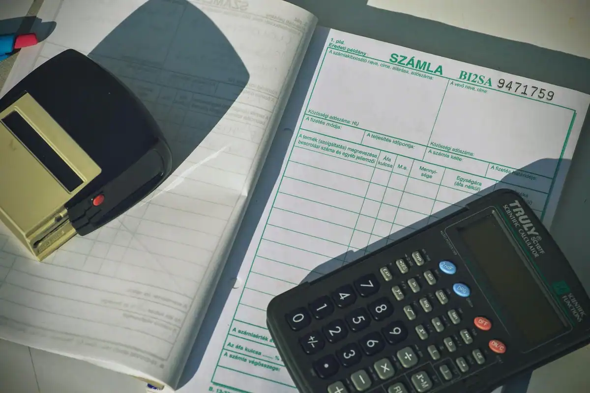 Bon fiscal și calculator pe un birou, printre hârtii, pentru calculul unei sume de returnat