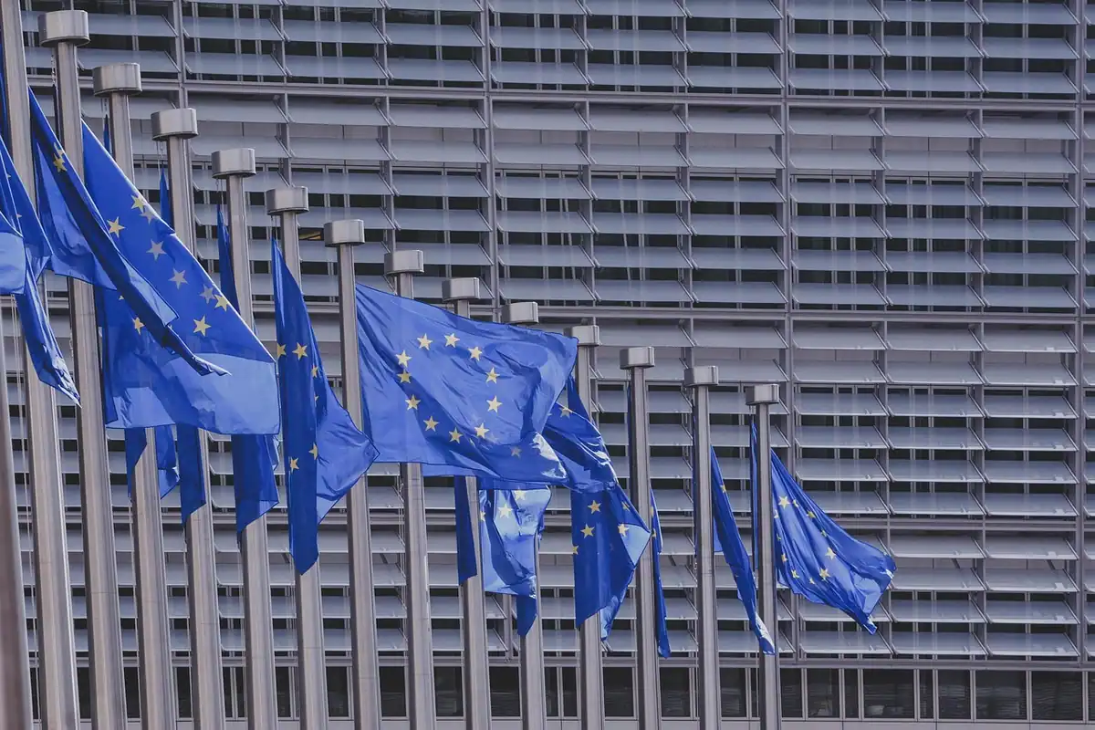Steaguri ale Uniunii Europene în fața unei clădiri cu fațadă din sticlă