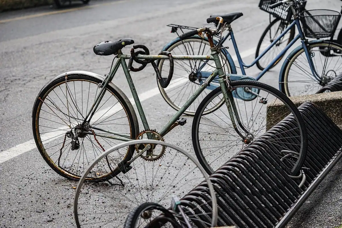 Bicicletă prinsă cu lanț de un stâlp pe o stradă din oraș, parcată pe trotuar