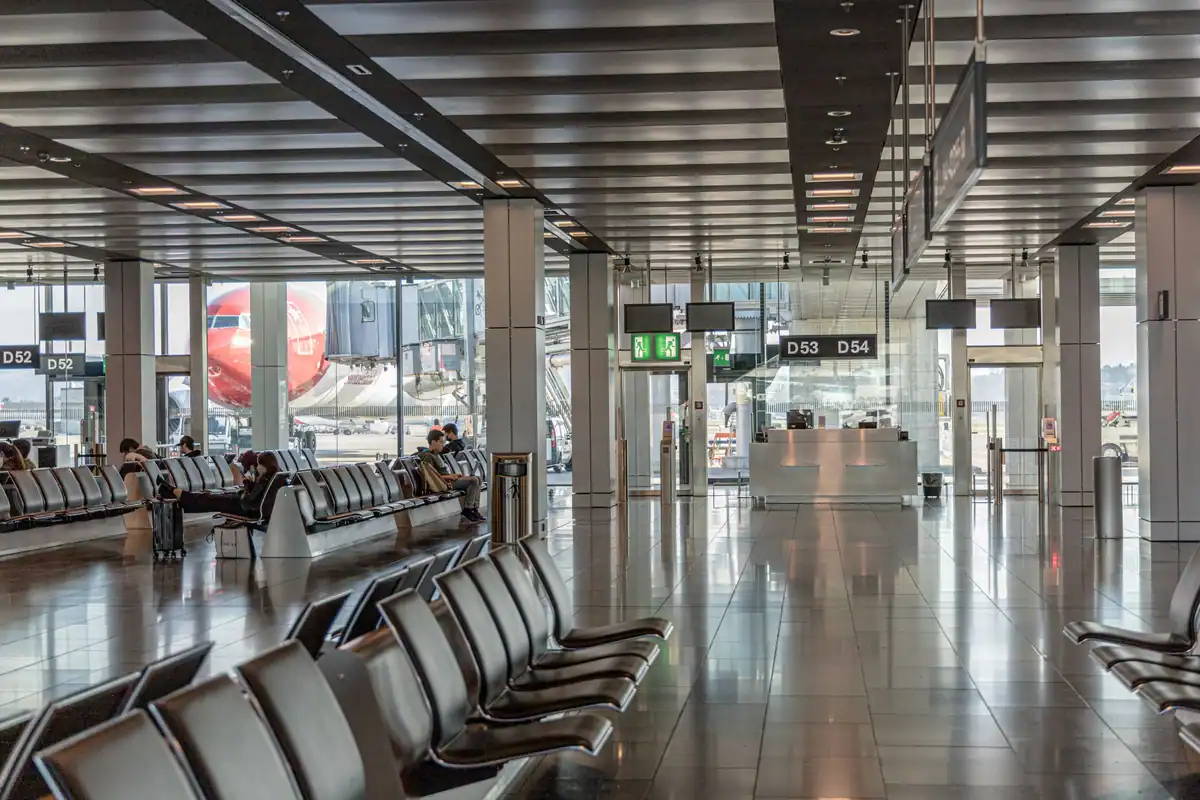Terminal de aeroport aproape gol, cu scaune de așteptare și avion în fundal