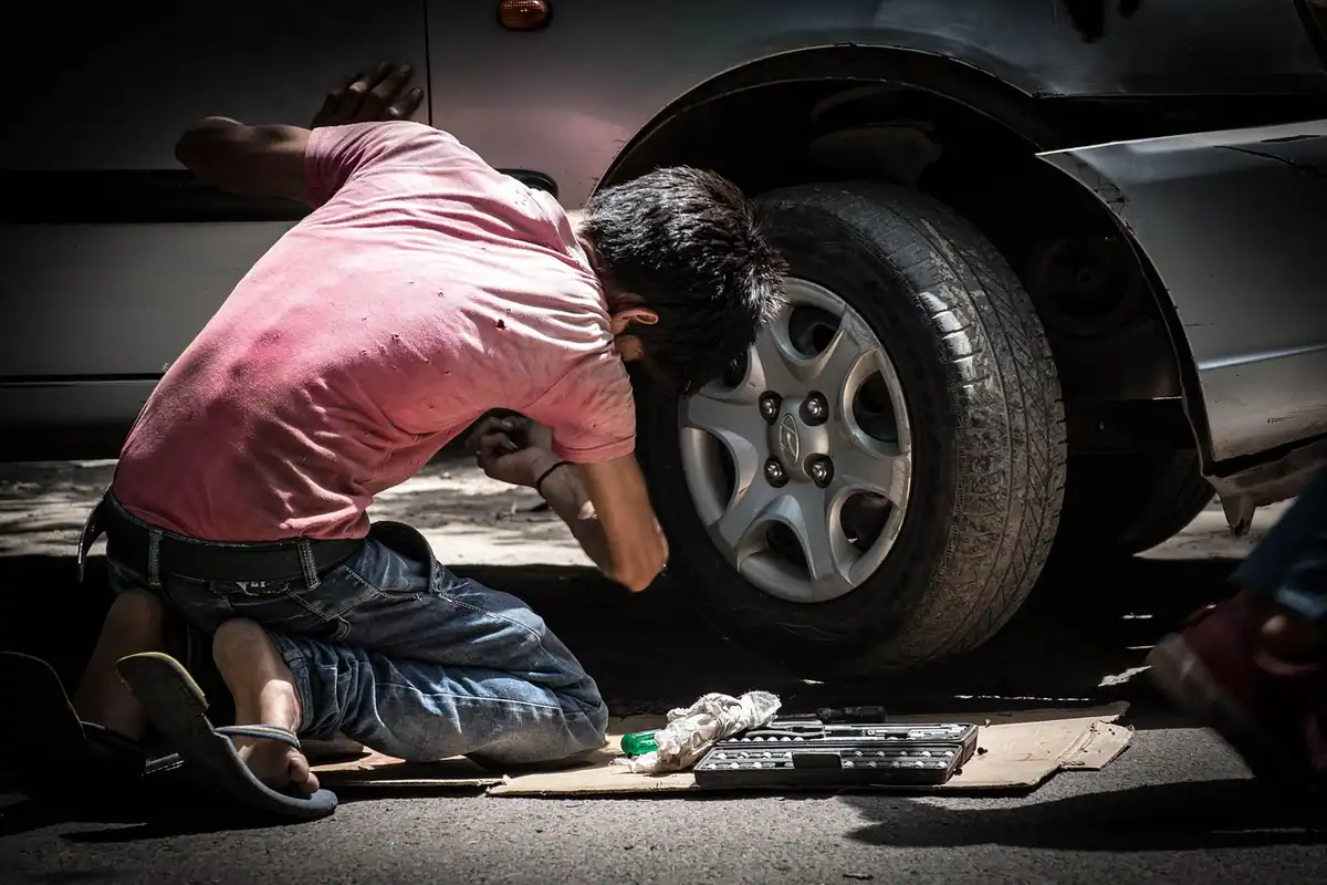 Trusă cu scule deschisă pe podea, lângă un tehnician de service care repară un aparat