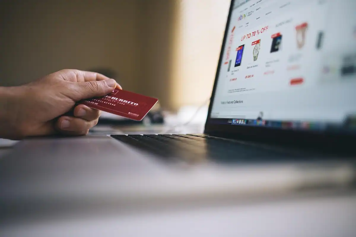 Pagina de finalizare a comenzii pe ecranul unui laptop, alături de câteva documente