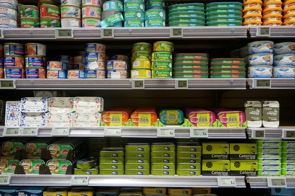 Etichetă de preț lipită pe un raft de supermarket, lângă produsele expuse