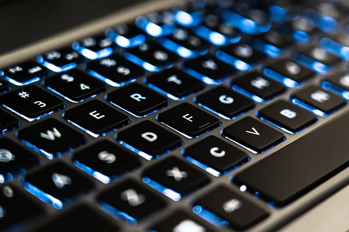 Tastatură de laptop cu taste negre, luminate în albastru
