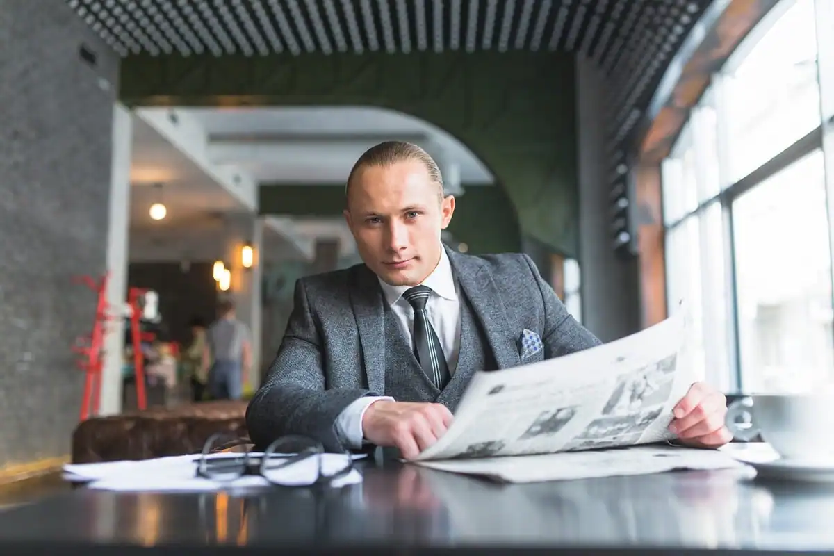 Persoană care citește o scrisoare la birou, cu o cană de cafea alături