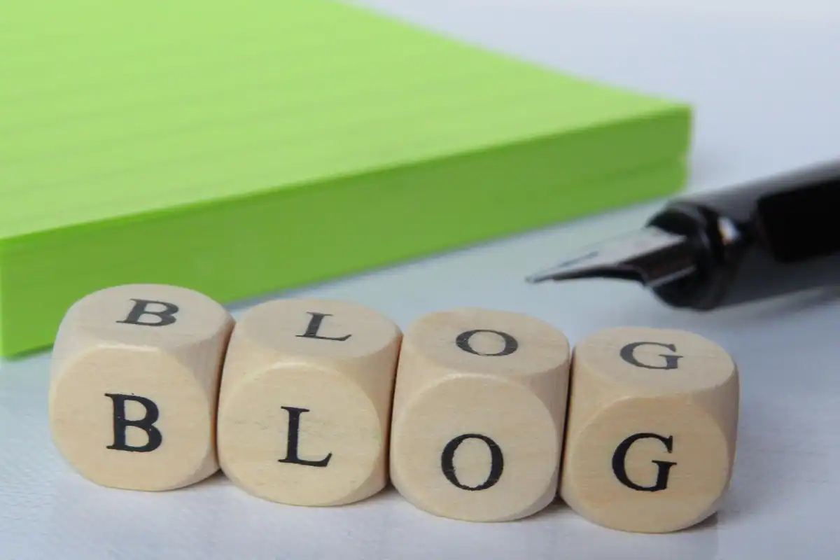 Laptop cu o pagină de blog deschisă, în timp ce cineva scrie un text